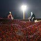 Two coffee mill workers sit at dusk on the wall of a soaking channel filled with freshly picked red coffee berries.