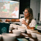 Valentina Duque standing behind a table full of white cupping bowls. She is rinsing her spoon in between sips.