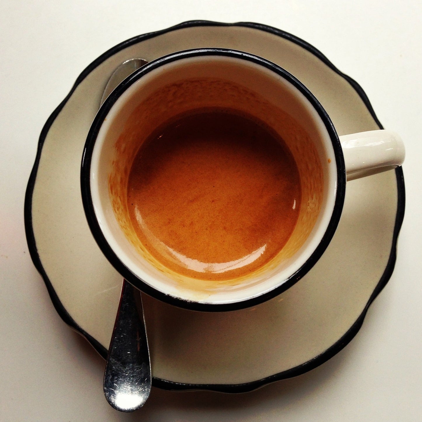 Beautiful espresso in a cream colored demitasse. Blue detailing. With saucer and demitasse spoon. Top down.