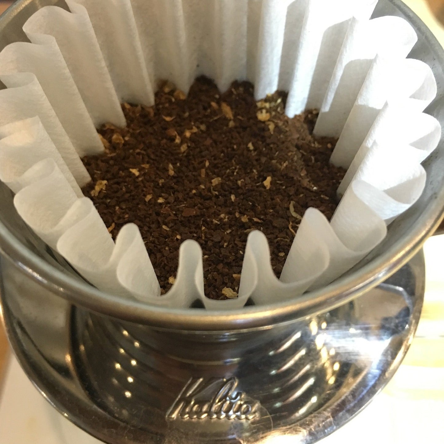 Close-up of Kalita Wave 185 with paper filter and medium-ground coffee